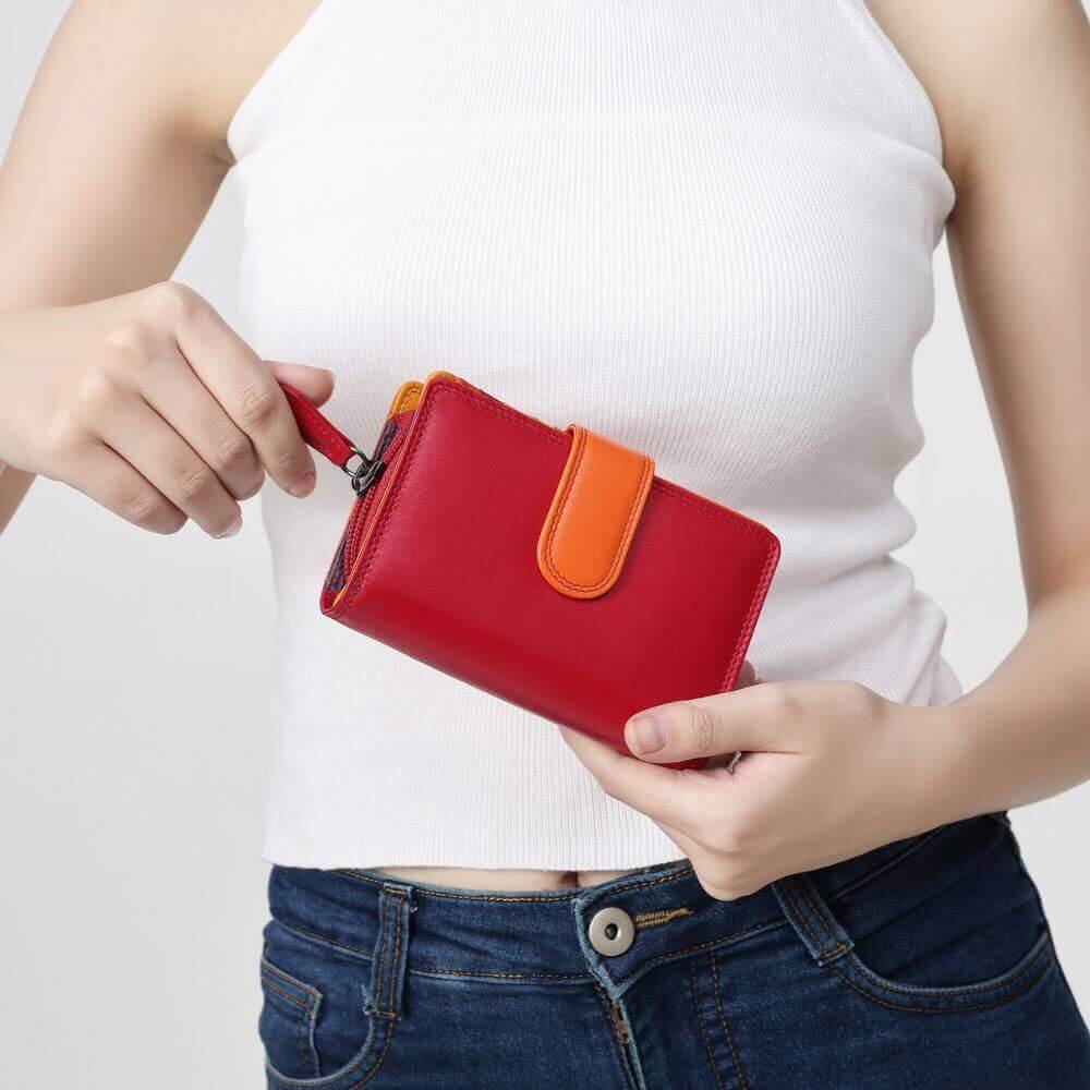 Person holding a red wallet with an orange strap against a white background