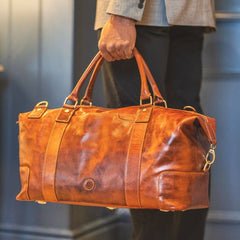 Man holding Orion tan full-grain leather holdall travel bag by Primehide, ideal for weekend travel.