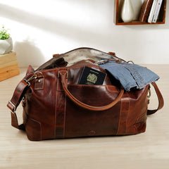 Orion tan leather holdall travel bag by Primehide open and packed with clothes, full-grain leather with brass fittings.